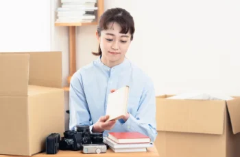 段ボール箱が積まれた片付いた部屋で不用品整理の準備をする様子