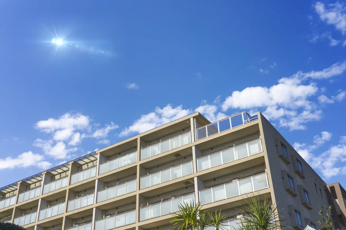 都市部に建ち並ぶマンションの外観と青空の風景