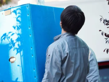 男性が大きな家具をトラックへ運び出している様子